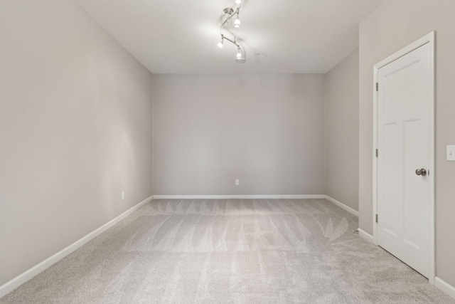 carpeted empty room featuring track lighting