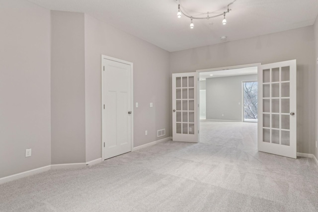 carpeted empty room with french doors and rail lighting