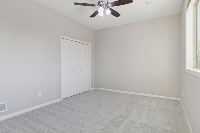 unfurnished bedroom featuring ceiling fan, light colored carpet, and a closet