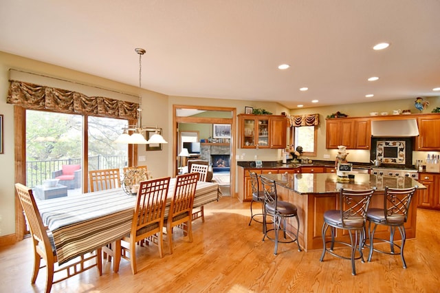 kitchen featuring pendant lighting, a center island, light hardwood / wood-style flooring, a fireplace, and a kitchen bar