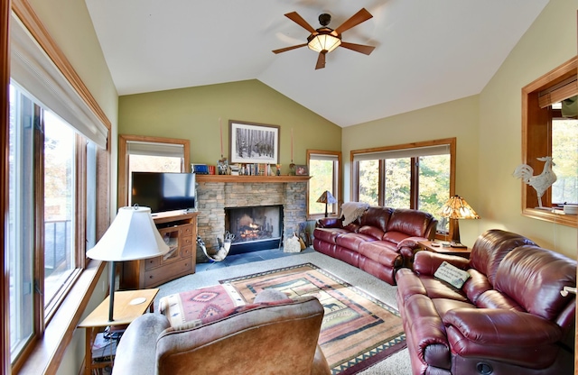 carpeted living room with ceiling fan, a stone fireplace, and lofted ceiling