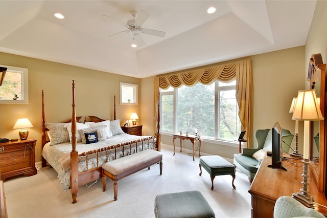 carpeted bedroom featuring a tray ceiling and ceiling fan