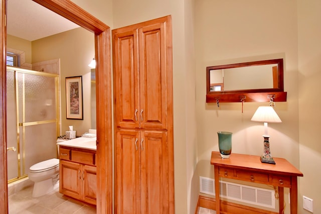 bathroom with tile patterned floors, vanity, toilet, and a shower with door