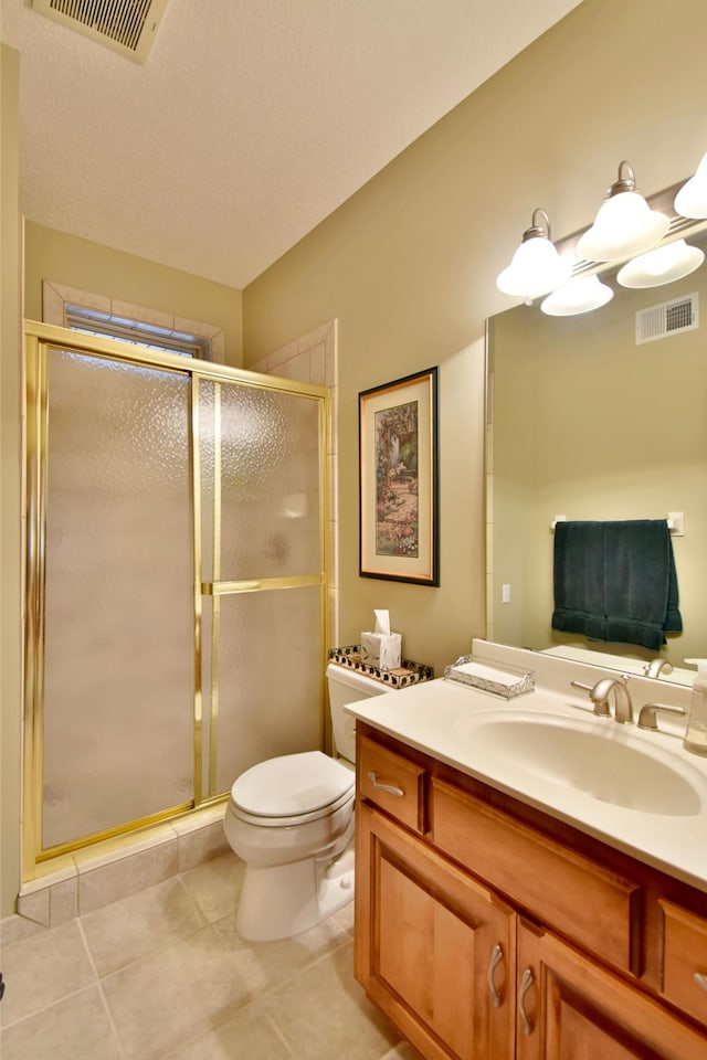 bathroom featuring tile patterned flooring, vanity, toilet, and an enclosed shower