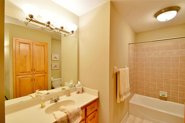 full bathroom with vanity, tiled shower / bath, and toilet