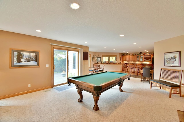 game room featuring a textured ceiling, light colored carpet, indoor bar, and billiards