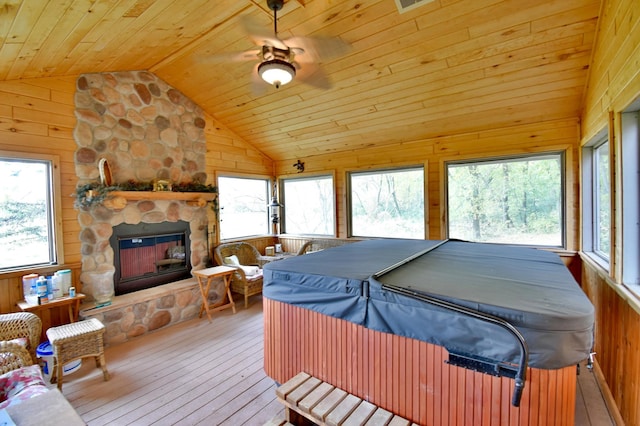 interior space with a stone fireplace, light hardwood / wood-style flooring, lofted ceiling, multiple windows, and wood ceiling