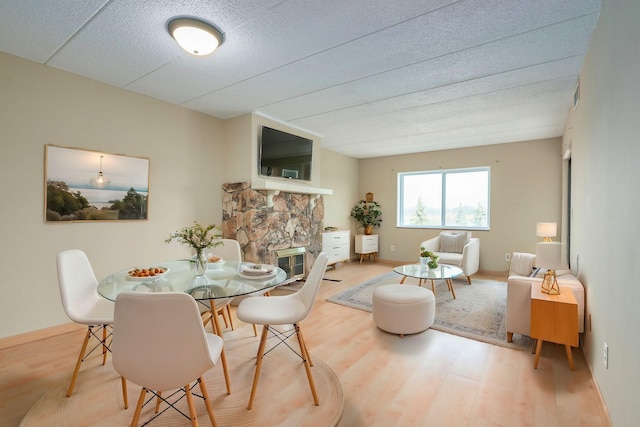 dining area featuring wood-type flooring and a stone fireplace