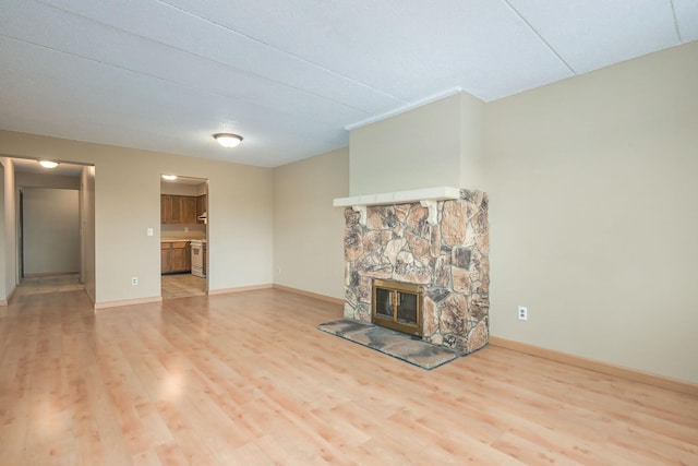 unfurnished living room with light hardwood / wood-style flooring and a stone fireplace