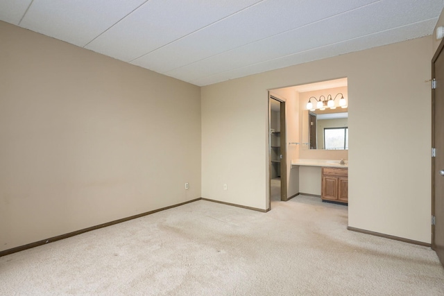 unfurnished bedroom featuring light carpet and ensuite bath