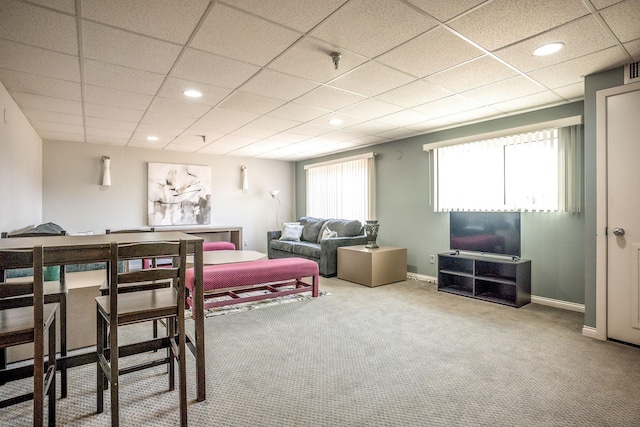 living room with a drop ceiling and carpet