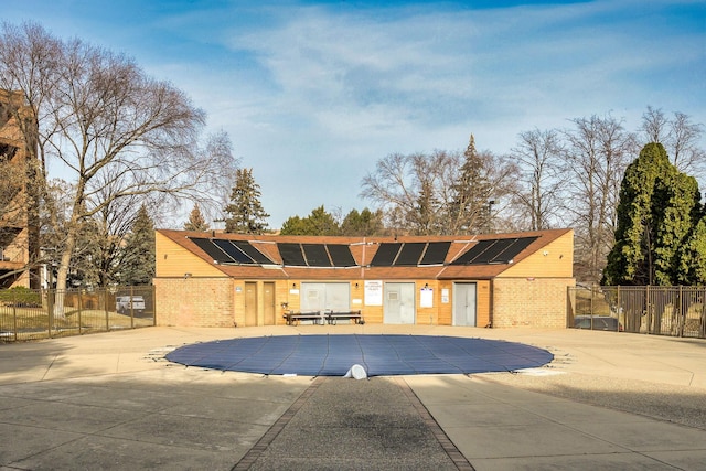 view of front facade with solar panels, a covered pool, and a patio area