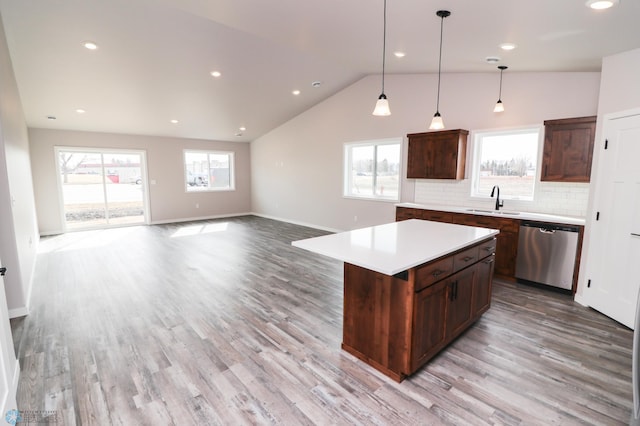 kitchen with backsplash, stainless steel dishwasher, vaulted ceiling, a kitchen island, and hanging light fixtures