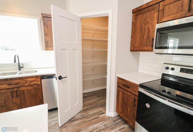 kitchen with sink, stainless steel appliances, tasteful backsplash, and light hardwood / wood-style flooring