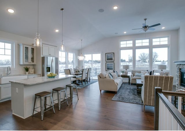 kitchen featuring a breakfast bar, sink, stainless steel fridge with ice dispenser, decorative light fixtures, and white cabinetry