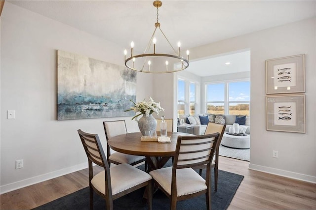 dining room featuring wood finished floors, a chandelier, and baseboards