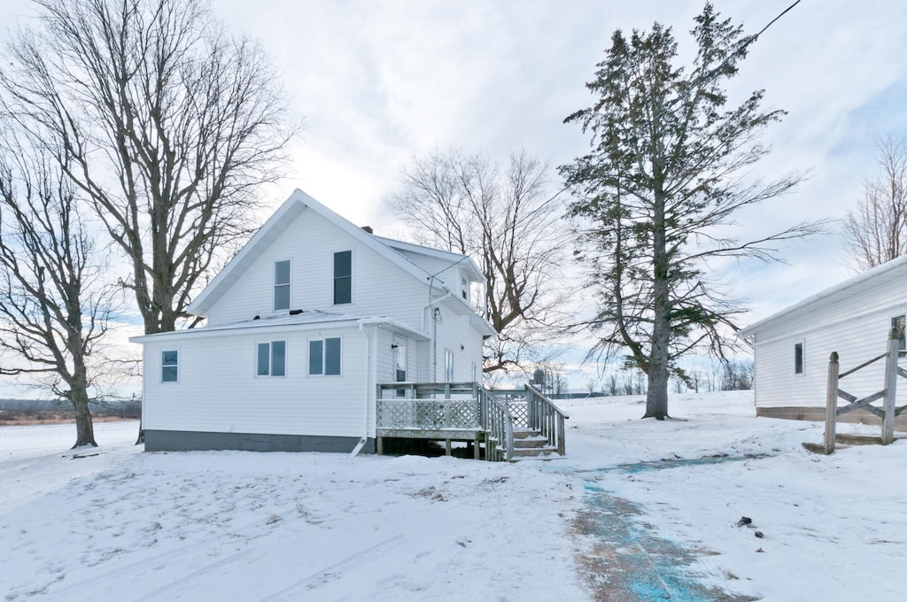 snow covered rear of property featuring a deck