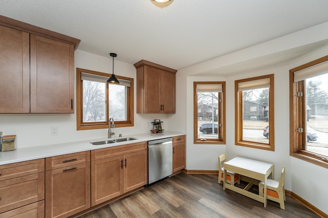 kitchen with dishwasher, dark wood-type flooring, hanging light fixtures, light countertops, and a sink