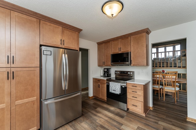 kitchen with dark wood-style floors, appliances with stainless steel finishes, light countertops, and a textured ceiling