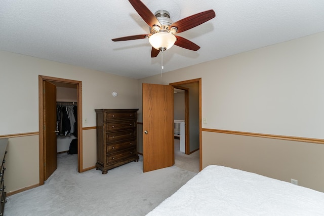 bedroom featuring light carpet, baseboards, a spacious closet, a textured ceiling, and a closet