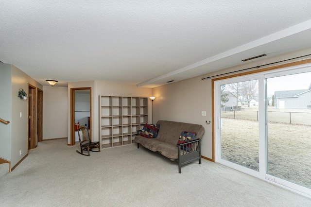 sitting room with carpet floors, visible vents, baseboards, and a textured ceiling