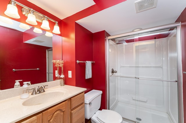 full bathroom featuring toilet, a stall shower, vanity, and visible vents