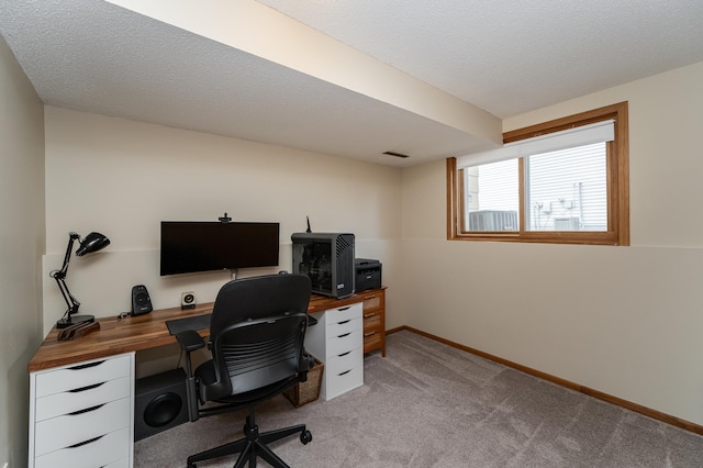 home office with a textured ceiling, baseboards, visible vents, and light colored carpet