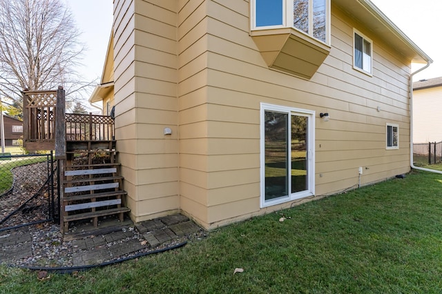 rear view of property featuring a yard, fence, and stairs