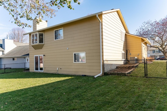 back of property featuring a gate, central AC, a lawn, and fence