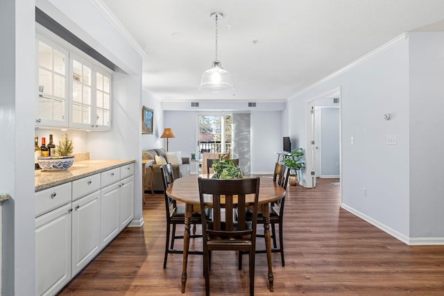 dining area featuring crown molding, indoor bar, and dark wood-type flooring