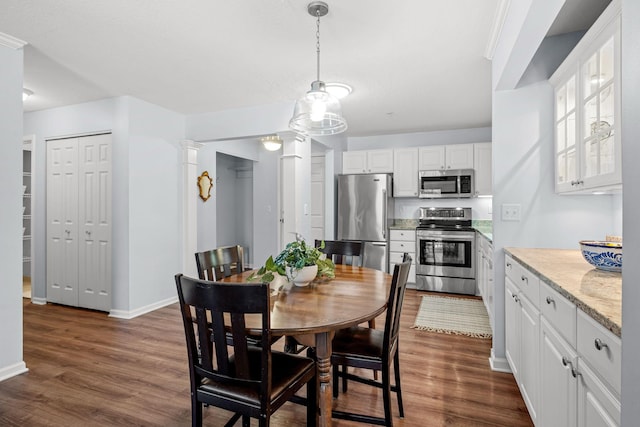 dining space with dark wood-type flooring and ornate columns