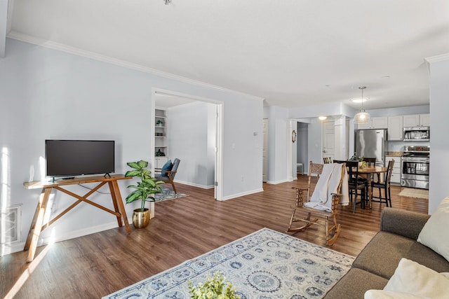 living room featuring built in shelves, hardwood / wood-style flooring, and crown molding