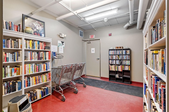 home office with wall of books, visible vents, and baseboards