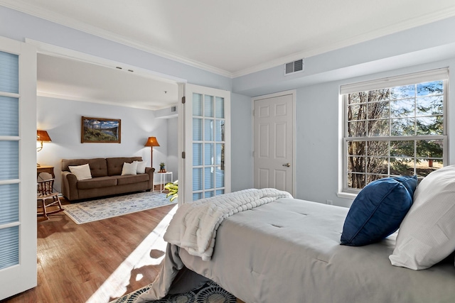 bedroom with ornamental molding, wood finished floors, and visible vents