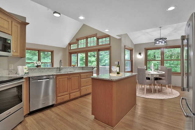 kitchen featuring sink, pendant lighting, vaulted ceiling, appliances with stainless steel finishes, and light wood-type flooring