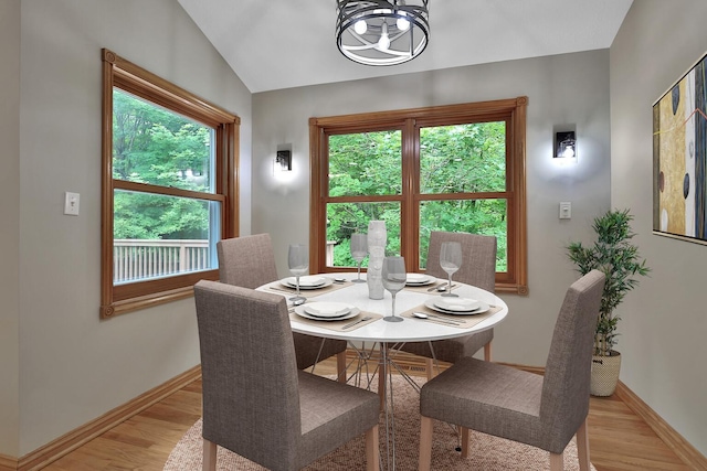 dining space featuring light wood-type flooring, vaulted ceiling, and a notable chandelier