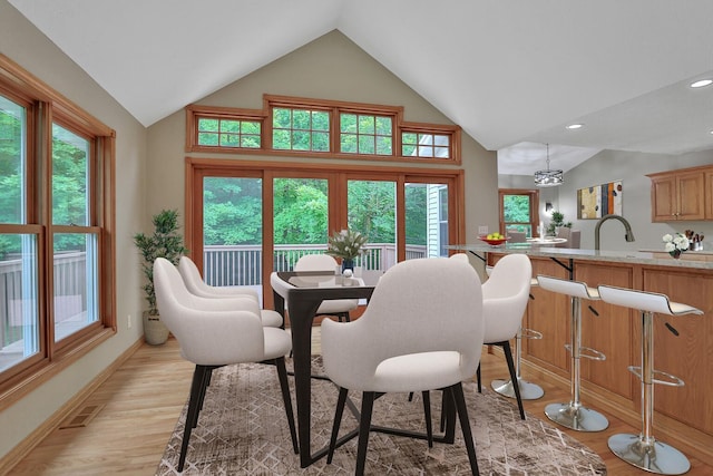 dining area featuring light hardwood / wood-style floors, lofted ceiling, and sink