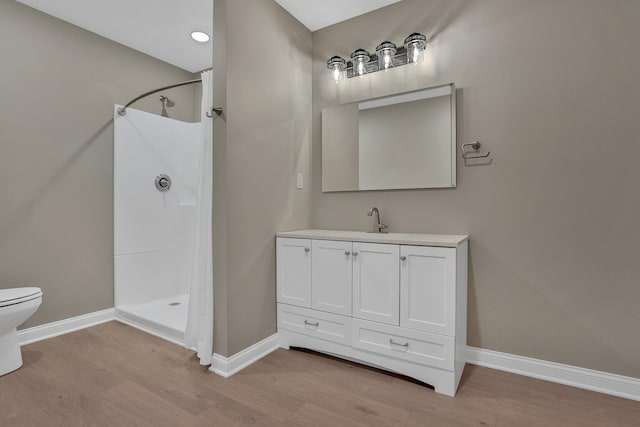 bathroom with wood-type flooring, vanity, toilet, and walk in shower