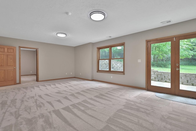 unfurnished room with light carpet, french doors, and a textured ceiling