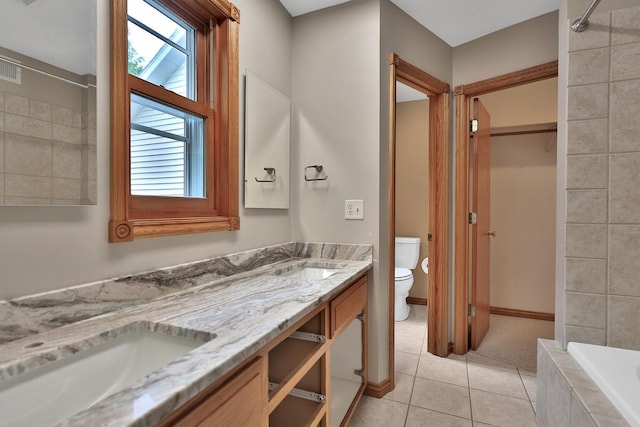 bathroom featuring tile patterned floors, vanity, a relaxing tiled tub, and toilet