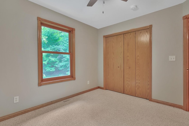 unfurnished bedroom featuring light carpet, a closet, and ceiling fan