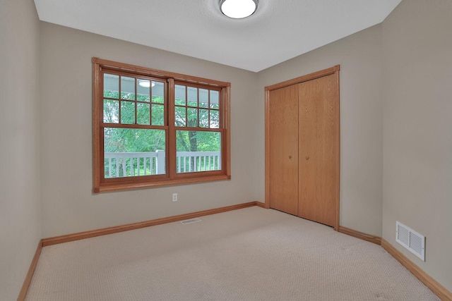 unfurnished bedroom with light colored carpet and a closet