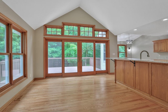 doorway with sink, french doors, a notable chandelier, light hardwood / wood-style floors, and lofted ceiling