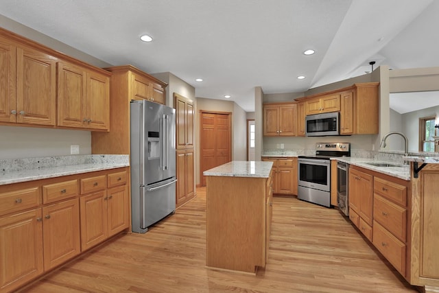 kitchen with a center island, sink, vaulted ceiling, light stone countertops, and stainless steel appliances