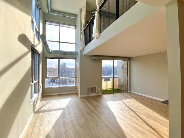 unfurnished living room featuring light hardwood / wood-style flooring and a high ceiling