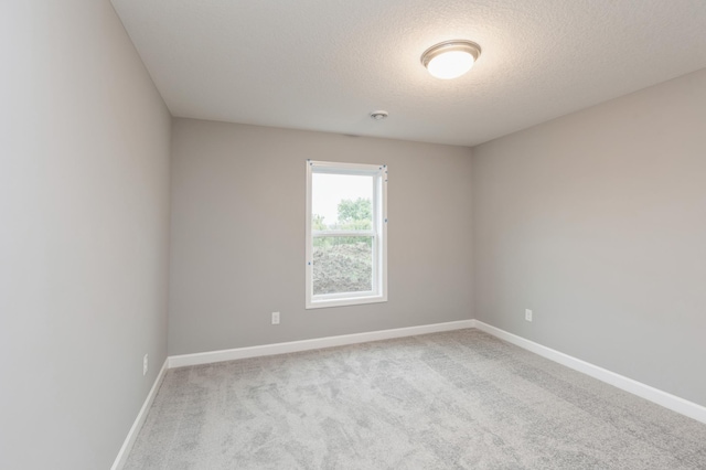 spare room featuring light colored carpet and a textured ceiling