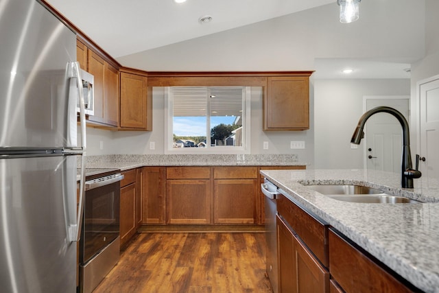 kitchen with lofted ceiling, sink, light stone counters, dark hardwood / wood-style flooring, and stainless steel appliances