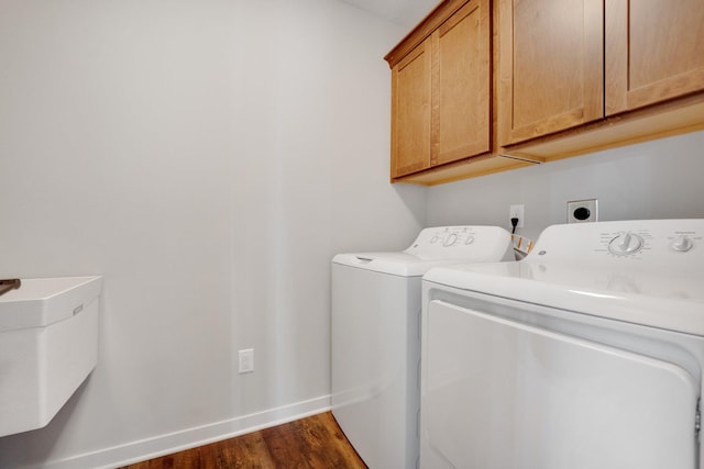 laundry room with dark wood-type flooring, washer and clothes dryer, and cabinets