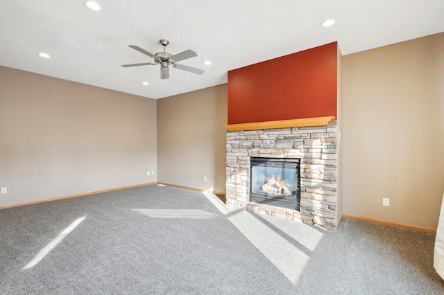 unfurnished living room featuring carpet flooring, ceiling fan, and a stone fireplace