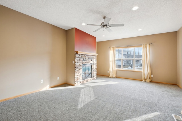 unfurnished living room with light carpet, a textured ceiling, a stone fireplace, and ceiling fan